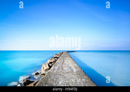 Beton und Felsen Pier oder Steg auf einen blauen Ozeanwasser. Lange Belichtung Fotografie Stockfoto