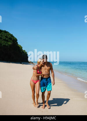 Aufnahme des jungen Mann und Frau zu Fuß auf den tropischen Strand. Romantisch zu zweit spazieren am Strand, Sommerurlaub genießen. Stockfoto