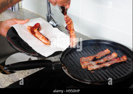 Afrikanische amerikanische Mann Kochen Speck auf Herd mit einer Grillpfanne Stockfoto