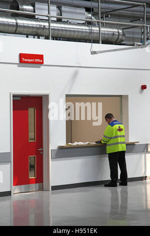 Ein Postbote wartet an der Rezeption Transport Office in ein neues Postamt Sortierung Büro im südlichen England, UK Stockfoto