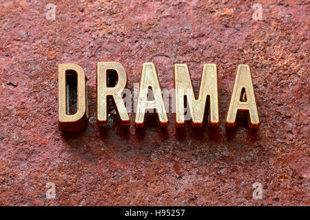 Drama-Wort, das aus metallischen Lettern auf rotem rostige Oberfläche Stockfoto