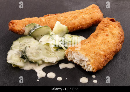 leicht beschichtet Wittling Filet und Gurke Salat mit Knoblauch-Salat-Sauce auf Schiefer Stockfoto