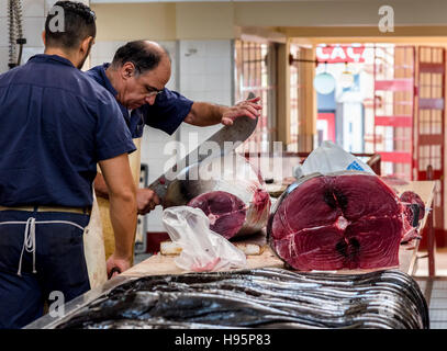 Arbeiter in der Fischmarkt zerschneiden ein riesiger Thunfisch mit einem riesigen Messer Stockfoto