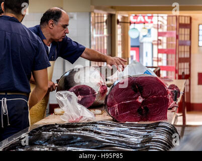 Arbeiter in der Fischmarkt zerschneiden ein riesiger Thunfisch mit einem riesigen Messer Stockfoto