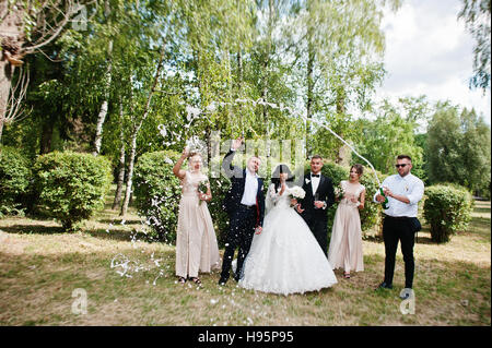 Stilvolle Hochzeitspaar, Brautführer und Brautjungfern mit Champagner Explosion. Stockfoto