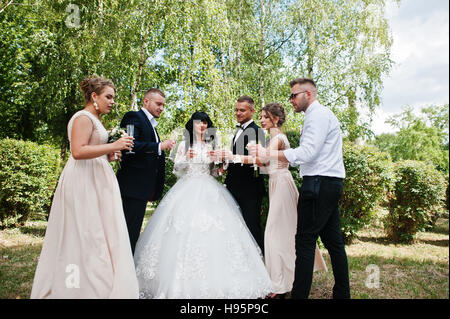 Stilvolle Hochzeitspaar, Brautführer und Brautjungfern outdoor Champagner trinken. Stockfoto