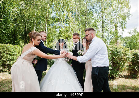 Stilvolle Hochzeitspaar, Brautführer und Brautjungfern outdoor Champagner trinken. Stockfoto