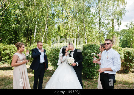 Stilvolle Hochzeitspaar, Brautführer und Brautjungfern outdoor Champagner trinken. Stockfoto