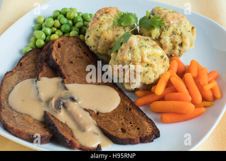 Seitan Steak mit Pilz-Sauce, Semmelknödel, frische Erbsen und Babykarotten Stockfoto