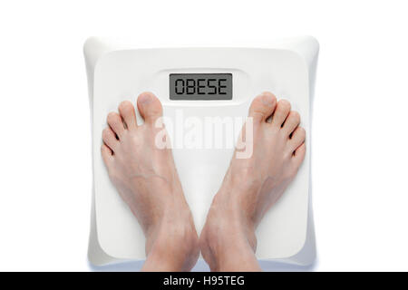 Füße auf Personenwaage mit dem Wort übergewichtige auf dem Bildschirm. Bedeutet entweder übergewichtig Gesundheitsprobleme. Stockfoto