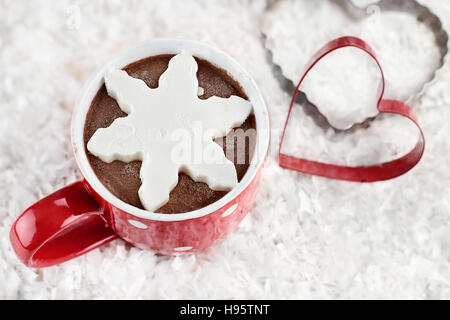 Über dem Schuss einer lebendige Rote Tasse heiße Schokolade mit Schnee Flocken Form von Schlagsahne. Extrem geringe Schärfentiefe. Stockfoto