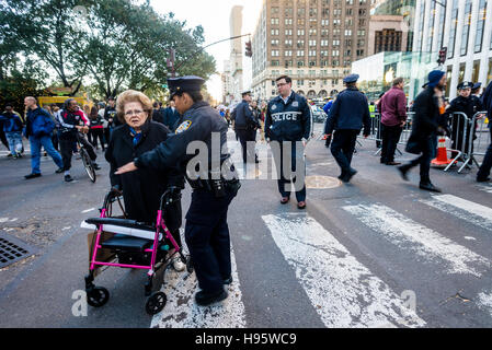 New York, USA 13. November 2016 - NYPD-Polizisten zu verhindern, dass eine Frau mit einer Gehhilfe vor der Kreuzung der Fifth Avenue aus Sicherheitsgründen um Trump Tower, Haus des Präsidenten wählen Donald Trump. New Yorks Bürgermeister Bill DeBlasio und der Secret Service angekündigt, Verkehrssperren und Sicherheit Meansure für den Zeitpunkt der Präsident Elect ist in der Stadt, im Vorfeld der Einweihung, und sagte die Stadt föderalen Reinbursement für Sicherheitskosten suchen würden. Stockfoto