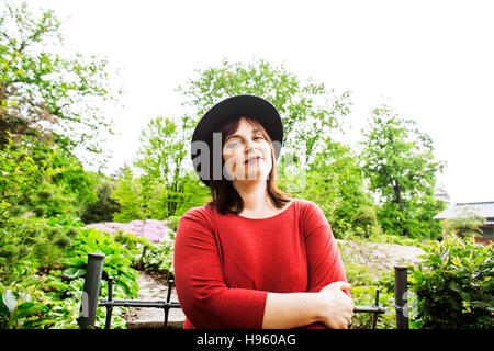 Reife Brünette Frau im grünen Garten tragen, Hut, Lächeln, frie Stockfoto