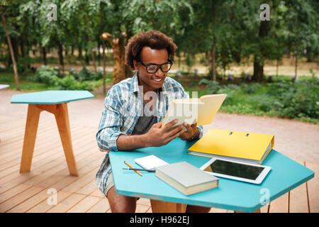 Glücklichen hübscher junger Mann Brille lesen und Zeit im Café im freien Stockfoto