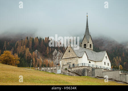 Nebligen Herbsttag an der berühmten Kirche San Lorenzo in Sauris di Sopra, Provinz Udine, Italien. Dolomiten. Stockfoto