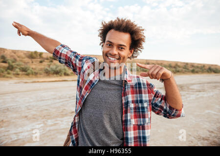 Portrait des Lächelns afrikanischen junge Mannes mit Rucksack weg zeigt, mit beiden Händen im freien Stockfoto