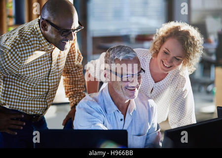 Lächelnde Geschäftsleute arbeiten am Computer im Büro Stockfoto