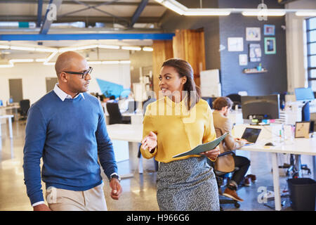 Unternehmer und Unternehmerin gehen und sprechen im Büro Stockfoto