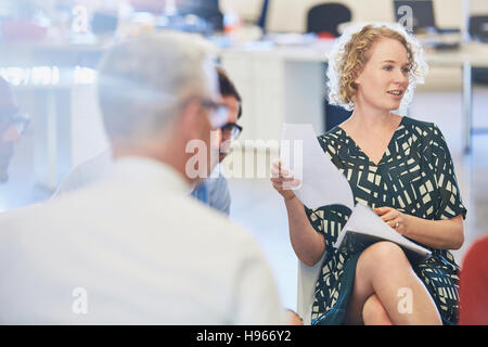 Geschäftsleute, die Papiere in Treffen diskutieren Stockfoto