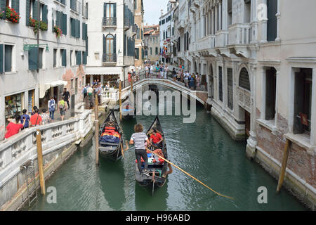 Gondoliere mit Touristen auf einem Kanal in Venedig. Stockfoto
