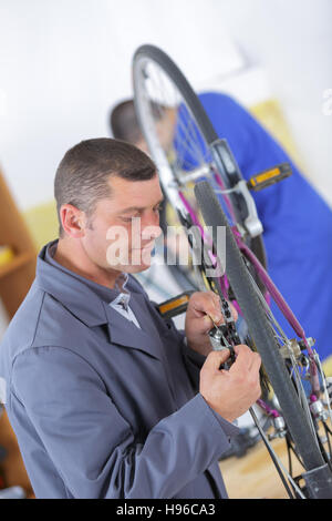 stilvolle Fahrradmechaniker seiner professionellen Arbeit in Werkstatt Stockfoto