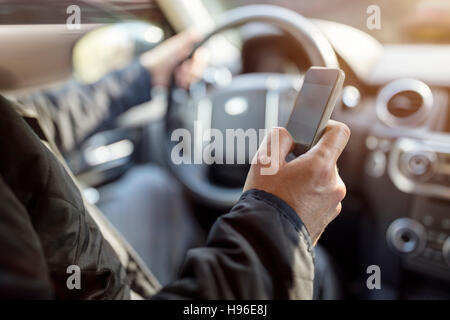 SMS während der Fahrt mit Handy im Auto Stockfoto
