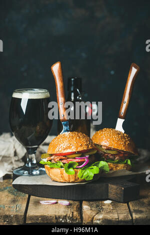 Rindfleisch-Burger mit knusprigem Speck und Glas dunkles Bier Stockfoto