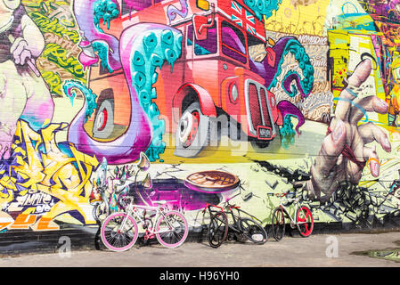 Große Mauer mit riesigen Wandbild Graffiti in der Nomadic Gemeinschaftsgärten, Shoreditch, East London, Vertretung rote Bus mit Krake im Inneren. Stockfoto