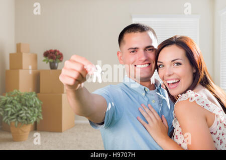 Glückliche junge militärische paar mit Hausschlüssel im leeren Raum mit voll beweglichen und Topfpflanzen. Stockfoto