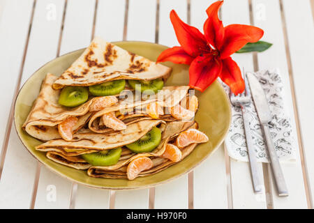 Hausgemachte Pfannkuchen gefüllt mit Marmelade und Früchten dekoriert mit roten Blume Stockfoto