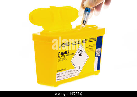 Eine medizinische sharps Abfallbehälter mit einer gebrauchten Spritze wird hineingesteckt. Stockfoto