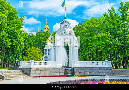 Die weiße Nische auf dem Siegesplatz mit dem Spiegelbrunnen und den hellen goldenen Kuppeln der Kirche der Heiligen Myrrhe-Träger auf dem Hintergrund, Charkiw, Ukraine Stockfoto