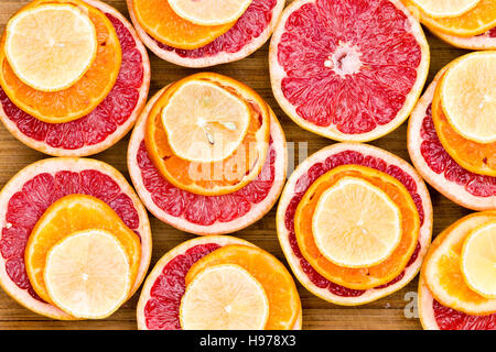 Full-Frame, High Angle View of geschnittenen Rubin rote Grapefruit gestapelt mit Reife Orangen und Zitronenscheiben auf rustikalem Holzbrett Stockfoto