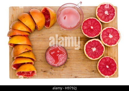 Ruby Grapefruit-Saft mit einer Draufsicht auf einem Bambus-Brett mit leeren Schwarten, saftige halbe Frucht, ein Krug und Glas frisch gepressten frisch vorbereiten Stockfoto