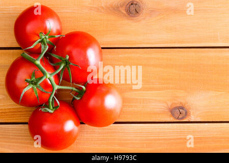 Top-down Ansicht auf fünf Hydrokultur rote Tomaten auf Stiel mit textfreiraum über unlackiert Holzbrett Tisch Stockfoto