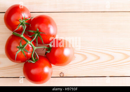 Fünf tiefrote reife mittelgroße Tomaten über unvollendete Holzbohlen. Textfreiraum umfasst. Stockfoto
