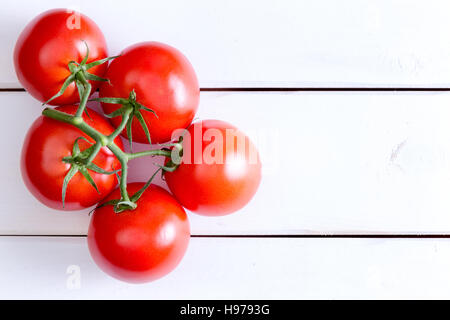 Top-down Ansicht auf fünf mittlerer Hydrokultur rote Tomaten auf Stiel mit textfreiraum über weiß lackierten Holztisch Stockfoto