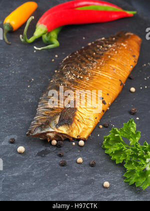 Geräucherte Makrele mit Pfeffer und Kochzutaten auf einem dunklen Schiefer Teller in der Küche Stockfoto