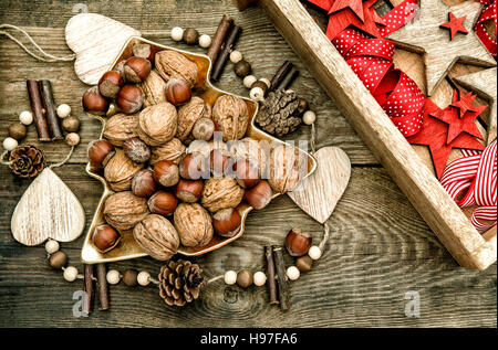 Walnüsse mit Weihnachtssterne Dekorationen aus Holz und roten Bändern. Vintage-Stil getönten Bild Stockfoto