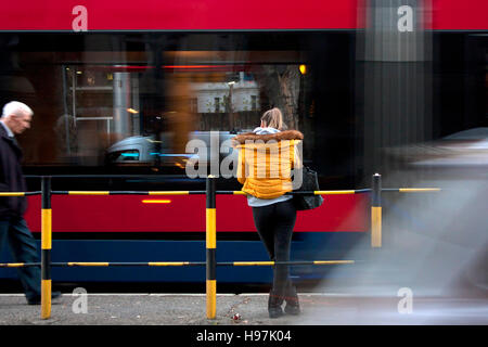 Junge Frau warten eine Straßenbahn auf Stadt, Straße, Autos, Straßenbahnen und ältere Mann vorbei in Motion blur Stockfoto