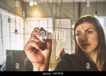 Kreative schöne Geschäftsfrau schreiben auf Glastafel im Büro Stockfoto