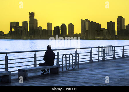 Zweifarbige Bild von einem Mann sitzen auf der Parkbank, den Sonnenuntergang über dem Hudson River in New York City Stockfoto