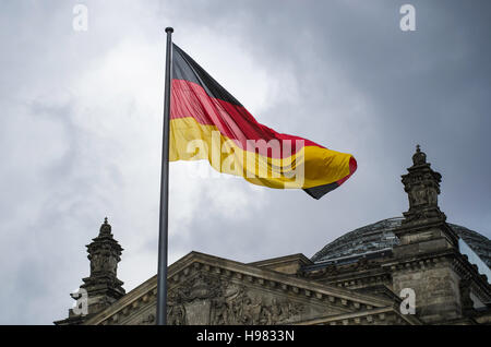 Deutsche Flagge weht über dem Reichstag Gebäude an einem ominösen Tag in Berlin Stockfoto