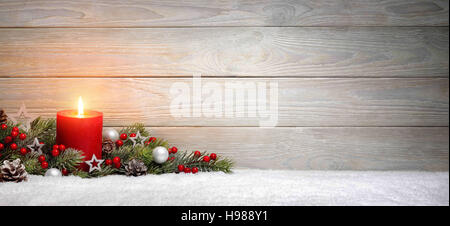 Weihnachten oder Advent Holz Hintergrund mit einer brennenden Kerze auf Schnee, dekoriert mit Tannenzweigen und Ornamente, Panorama-Format mit Textfreiraum Stockfoto