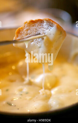 Käse-Fondue - ein Stück Brot Croutons in einen flüssigen Käse Stockfoto