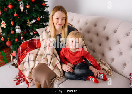 Mutter und Sohn sitzen in der Nähe von einem Teppich bedeckt Bäume Stockfoto