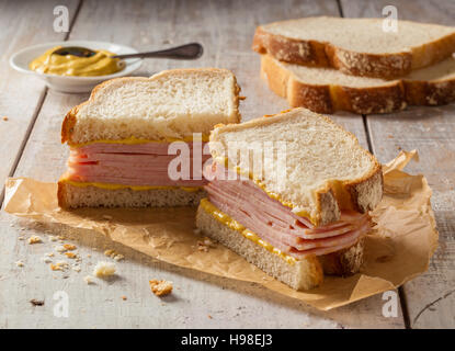 Ein geräuchertes Fleisch Sandwich auf einem Holztisch mit Senf. Stockfoto