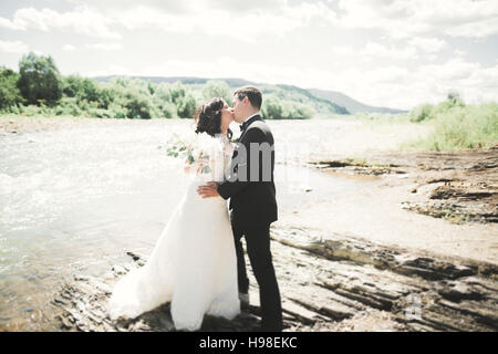 Elegante stilvolle glücklich Brünette Brautpaar wunderschön auf dem Hintergrund von einem wunderschönen Wasserfall in den Bergen Stockfoto