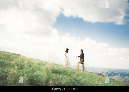 Schöne fabelhafte glückliche Brautpaar stilvolle posiert auf dem Hintergrund der sonnigen atemberaubende Berge Stockfoto