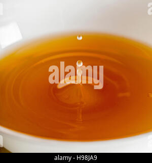 Wasser Tropfen fallen in einer Brühe, klare Suppe in eine weiße Tasse Stockfoto